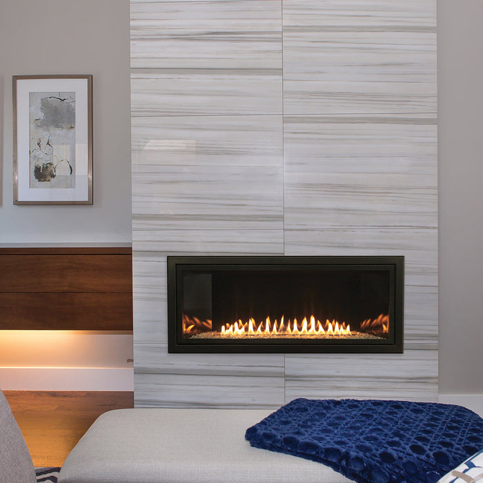 Empire Boulevard 36 inch linear gas fireplace in a tall tiled wall beside a bench