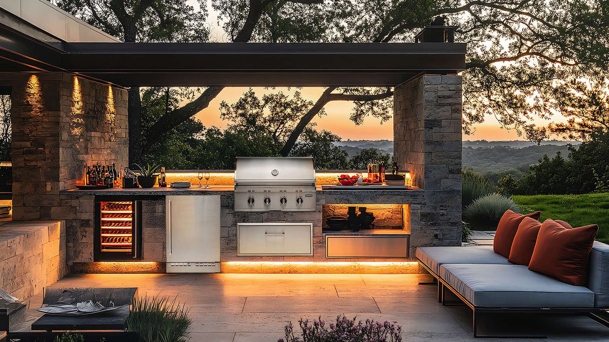 Coyote CL-Series built-in gas grill in a stone outdoor kitchen island at sunset