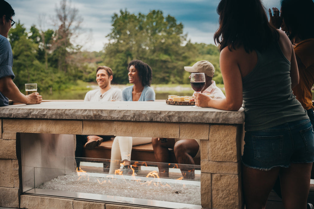 Empire Carol Rose 48 outdoor see-through linear fireplace on a lakeside deck with guests at the ledge