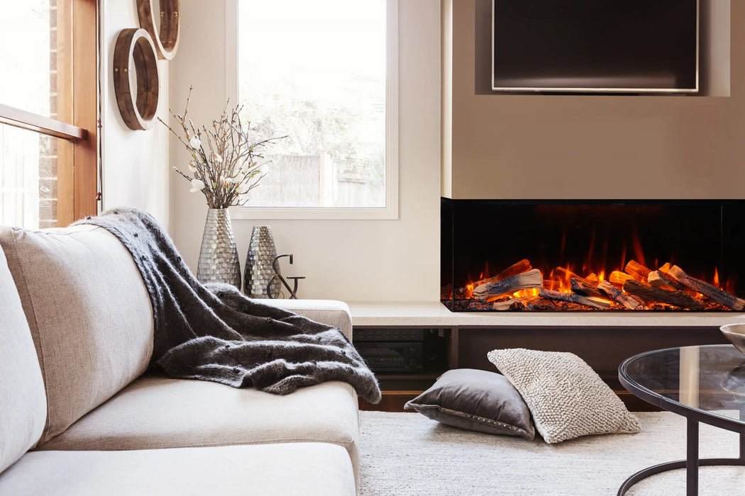 Amantii Fire & Ice LumaForest Built-In 3-Sided Electric Fireplace - installed in a corner beside a white sofa with a throw