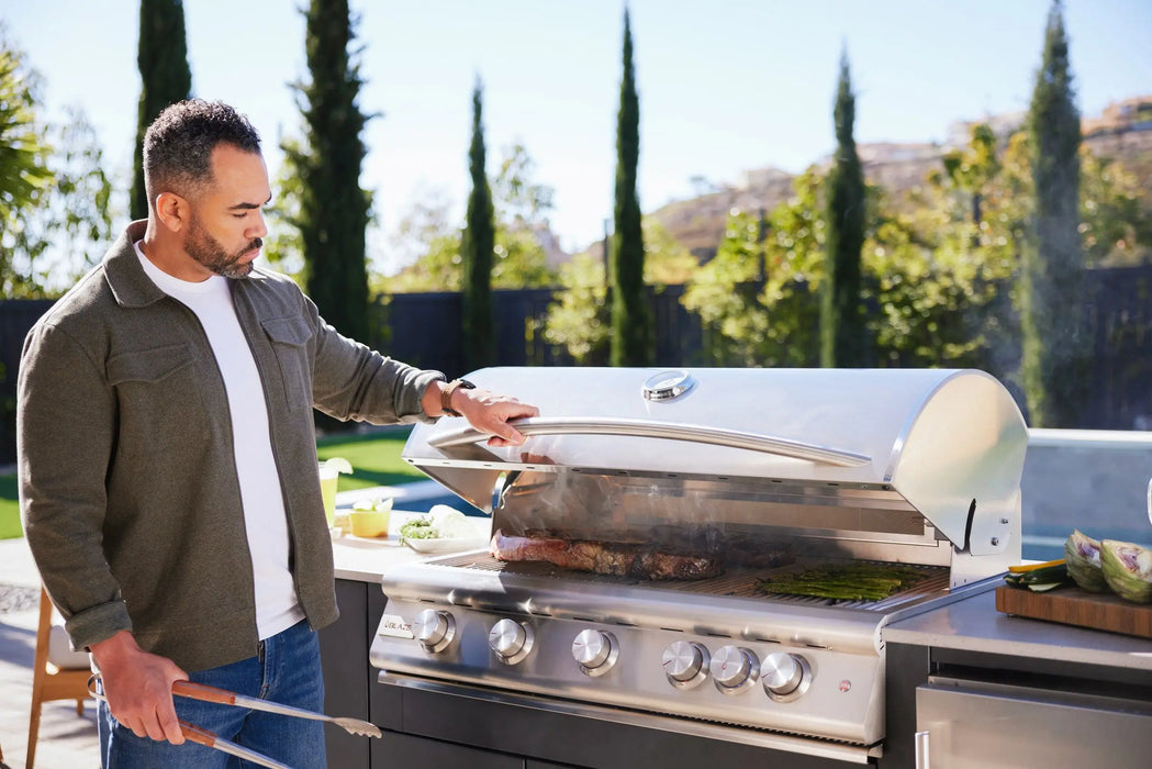 Man opening the hood of a Blaze LTE+ 40" gas grill built into an outdoor kitchen