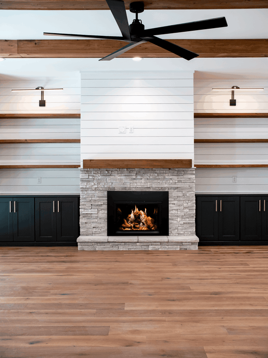 Empire Rainier 34 insert with birch logs and black glass in a stacked stone surround with shiplap and ceiling fan