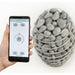HUUM mobile app on a smartphone beside a HIVE sauna heater
