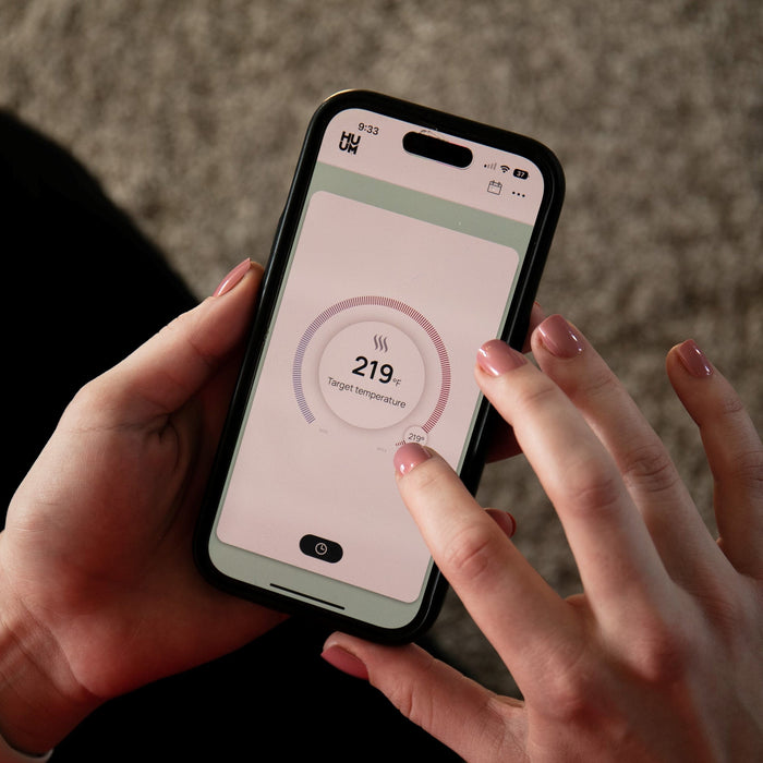 HUUM mobile app on a smartphone showing the sauna temperature dial