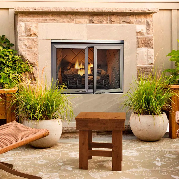 Majestic Vesper Outdoor Firebox With Refractory - installed in a stone surround with glass doors on a patio