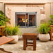 Majestic Vesper Outdoor Firebox With Refractory - installed in a stone surround with glass doors on a patio