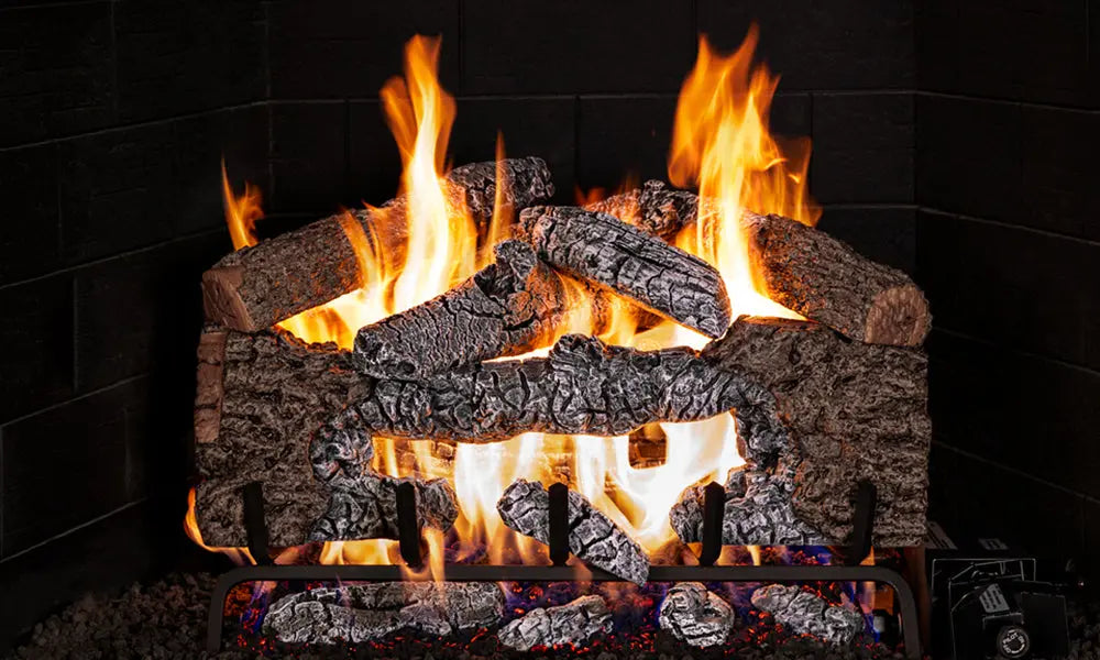 Charred Cinder Oak gas logs burning on a black background, with glowing embers and wood chunks in front
