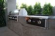 Wildfire Ranch Pro 42" gas grill and 30" griddle in black stainless steel with brushed bronze Designer Finish hardware in a stone island, hood closed
