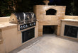 Wildfire Ranch Pro 42" gas grill in black stainless steel built into an island beside a pizza oven, at night