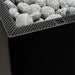 Close-up of the HUUM CORE Black sauna heater top grate filled with sauna stones