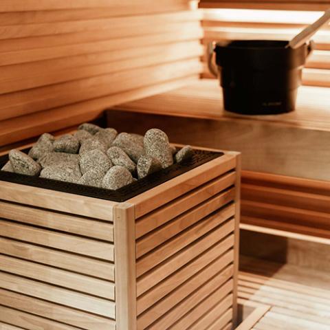 HUUM CORE sauna heater with thermo-aspen panels set beside a sauna bench