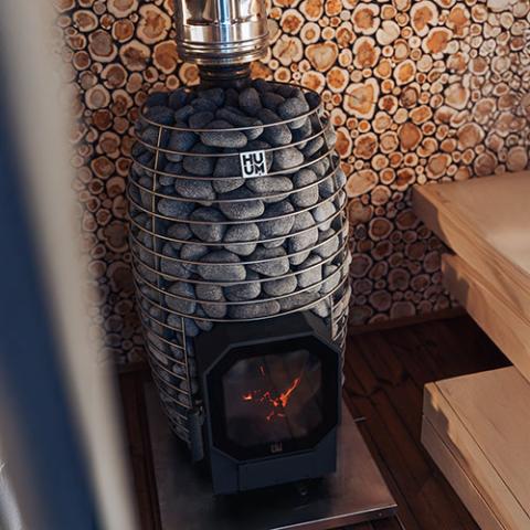 HUUM HIVE Flow wood-burning sauna stove installed in a sauna room