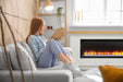 SimpliFire Modern Farmhouse Boyd build-out kit with Allusion Platinum 50" fireplace behind a gray sofa in a sunny living room